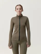 Chaqueta entallada de tejido técnico con cierre frontal completo, cuello alto y mangas largas con aberturas para pulgares. Presenta un diseño de texturas acanaladas verticales.