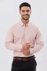 Camisa lisa de manga larga de algodón color rosado, con cuello camisero, botonadura frontal y un bolsillo aplicado en el pecho.