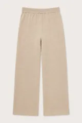 Pantalón de punto color beige, de corte recto y holgado. Presenta cintura elástica con cordón de ajuste y costuras verticales decorativas en el frente.