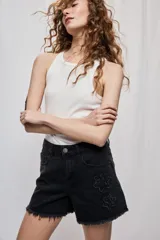 Short de denim blanco de calce recto y tiro medio, con bolsillos delanteros, cierre con botón y terminación desflecada en el ruedo. Presenta detalles florales bordados al tono en el frente.