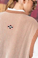 Chaleco de punto color beige con rayas verticales marrones y cuello redondo.