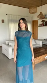 Vestido largo de microtul bordó, sin mangas, con escote alto tipo buche y diseño transparente con forro corto interno que genera un efecto translúcido en la falda.