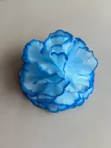 Accesorio para el pelo en forma de flor de tela azul, con bordes en tono azul más oscuro.
