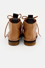 Borcego de cuero color marrón con diseño de costuras tipo mocasín en la puntera, cordones jaspeados y suela de goma con plataforma en capas.