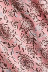 Vestido corto de gasa arrugada en color rosado con estampado floreado, escote en V y costura fruncida central con botones decorativos forrados. Cuenta con mangas globo largas con puños elásticos y cierre oculto en la espalda.
