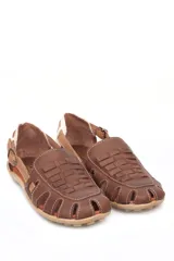 Sandalia tipo chatita color marrón, confeccionada en cuero con diseño de tejido trenzado en la puntera y el empeine. Presenta cierre de hebilla lateral y suela de goma con textura.