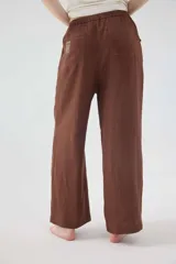 Pantalón de lino color beige, de silueta relajada, tiro medio-alto, cintura elastizada con cordón ajustable, bolsillos laterales y bolsillos traseros.