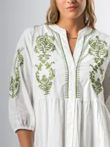 Vestido corto blanco de algodón italiano, con mangas tres cuartos, bordado floral verde en el frente y botones en todo el largo. Tiene forro interior en la falda.