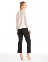 Buzo blanco de tejido liviano soft, marca Pinch. Cuello a la base realzado con una banda de micro-strass plateado. Mangas largas de corte recto con terminación de puño fino.