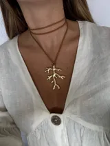 Collar con cordón marrón y dije dorado en forma de rama.