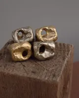 Anillo dorado con forma irregular y un agujero en el centro.
