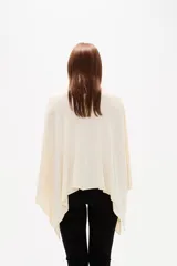 Poncho negro de tejido de punto con escote en V, diseño asimétrico y corte holgado.