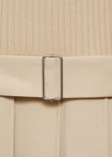Vestido midi de diseño combinado con cuerpo de punto acanalado en color beige, cuello en pico y manga larga. La falda es de corte evasé con diseño de tablas, trabillas y cinturón desmontable con hebilla metálica.