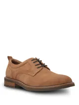 Zapato de vestir tipo derby marca Hush Puppies, confeccionado en cuero gamuzado color tostado. Presenta cordones oscuros, costuras reforzadas y suela de goma con efecto moteado.