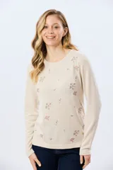 Buzo tejido de algodón color beige con cuello redondo, manga larga y delicados detalles bordados de flores.