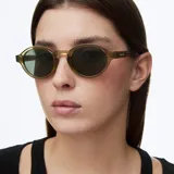 Lentes de sol con montura redonda de diseño retro, fabricada en material bio-based color verde traslúcido. Cuenta con lentes polarizadas en tono verde oscuro con protección UV400.