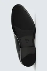 Bota Chelsea de cuero marrón, con punta fina y elásticos laterales oscuros. Posee un tirador trasero y un taco bajo y cuadrado.