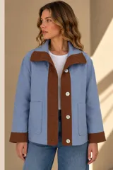 Campera marrón de lino con diseño bicolor, con una franja central gris claro que incluye botones de nácar. Cuenta con cuello alto, mangas largas con puños grises, bolsillos frontales aplicados y silueta amplia.