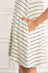 Vestido corto de lino color crudo con rayas horizontales negras, corte suelto, cuello redondo y mangas cortas.