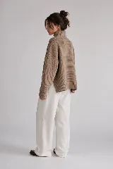 Sweater tejido de punto color blanco, con cuello alto tipo media polera, mangas largas y dobladillo asimétrico con aberturas laterales.