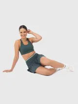 Top deportivo de sujeción baja, color verde oscuro, con escote redondo y espalda estilo nadadora. Cuenta con almohadillas removibles y diseño ergonómico para mayor comodidad.