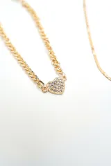 Set de cuatro pulseras doradas de diferentes diseños: una con cristales incrustados, una fina con dijes colgantes, una de cadena tipo víbora y una de cadena gruesa con un dije de corazón pavé.