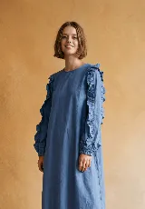 Vestido midi de corte holgado en color verde oliva, con mangas largas abullonadas que presentan detalles de volados en los hombros y puños elásticos.