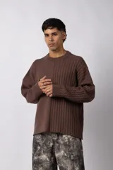 Sweater de punto color blanco con diseño de textura combinada, presentando un lado liso y otro con tejido trenzado. Posee cuello redondo, mangas largas y un corte relajado.