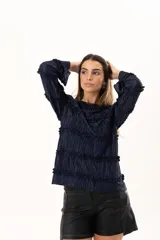 Blusa de manga larga en color azul marino, confeccionada en tejido plisado con detalles de volados horizontales a lo largo de toda la prenda.