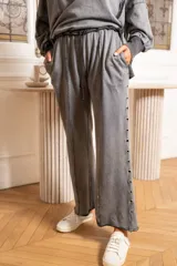 Pantalón gris de algodón con efecto vintage, corte ancho, cintura elastizada con cordón ajustable y detalle de ojales metálicos en los laterales.