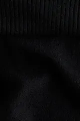 Buzo de punto negro, corte corto y ajuste entallado, con escote amplio que se puede usar caído sobre los hombros (off-the-shoulder) y cuello doblado acanalado.