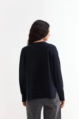 Sweater de tejido de punto color azul marino, con cuello abierto tipo polo y tajos laterales en el ruedo. Presenta mangas largas con puños acanalados y un corte holgado.