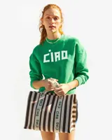 Bolso tote de lona a rayas verticales marrones y blancas con asas de mano y estampado "Ciao" en las asas.