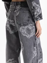 Pantalon de denim con lavado gris y estampado floral en contraste. De tiro medio y pierna amplia, presenta un calce relajado, bolsillos clásicos y cierre con botón metálico.
