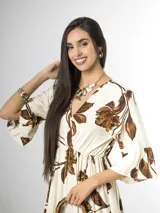 Vestido largo color crudo con estampado floral marrón, escote en V cruzado, mangas tres cuartos con volados y falda con niveles fruncidos.