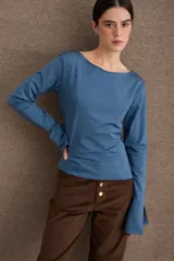 Remera de manga larga en color azul, con cuello bote y diseño ajustado al cuerpo. Presenta un acabado de borde sin costuras en el cuello y puños con abertura lateral.