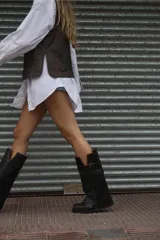 Bota de cuero marrón con diseño 2 en 1, que permite usarla con o sin polaina. Presenta una suela track robusta, cierre lateral y una tira con hebilla metálica en la parte superior de la caña.