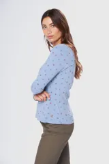 Remera de manga larga con cuello redondo, confeccionada en tejido suave con estampado de pequeñas hojas en tonos azul y rojo sobre fondo celeste.