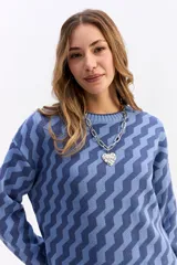 Buzo de punto con diseño geométrico en zigzag, de cuello redondo y manga larga. Presenta un calce holgado y cómodo con puños y ruedo acanalados.