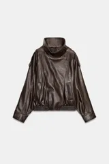 Cazadora tipo biker de cuello subido y manga larga, confeccionada en material efecto piel con textura granulada. Presenta trabillas en los hombros, bolsillos laterales de vivo, bajo elástico y cierre frontal cruzado con cremallera oculta y botones forrados.