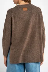 Sweater de punto texturado en color beige, con cuello redondo y mangas largas. Presenta un diseño de tejido acanalado vertical y corte holgado.