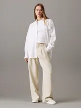 Pantalón de vestir color beige, de corte recto y tiro alto, confeccionado en crepé elástico. Presenta cintura plisada, bragueta con cremallera y cierre oculto, bolsillos laterales y traseros de ojal.