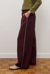 Pantalon de corte recto y pierna ancha, confeccionado en tejido tipo denim oscuro. Presenta tiro alto, cintura con cierre frontal y bolsillos laterales funcionales.