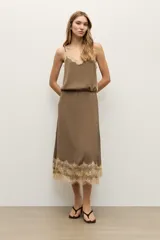 Falda midi color topo, confeccionada en tela fluida, con detalle de encaje en tono crudo en el ruedo.