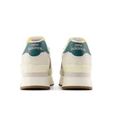 Championes urbanos New Balance modelo 574, color crema con detalles en blanco, verde y marrón, confeccionados en gamuza y malla, con logo "N" característico en los laterales y entresuela alta.