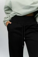 Pantalón blanco de silueta amplia y caída fluida, con cintura alta elastizada y lazo regulable con terminaciones metálicas.