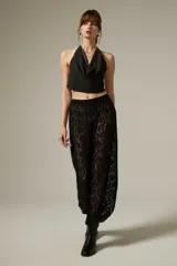 Pantalón tipo babucha de encaje negro con diseño floral, de corte holgado y cintura elástica.