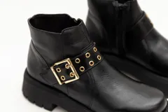 Borcego de cuero negro con plataforma y hebilla dorada decorativa.