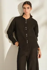 Camisa de lino italiano color negro, con cuello mao, manga larga, cierre frontal de botones y un bolsillo aplicado en el pecho.