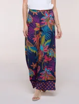Pantalón pull on largo de caída fluida, cintura alta con pretina trasera elastizada, pierna de corte ancho tipo palazzo y detalle de guarda geométrica sobre el ruedo inferior, con estampado floral multicolor sobre base azul.